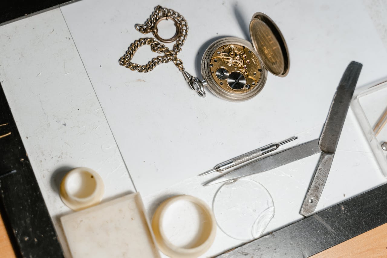 Detailed view of pocket watch mechanics with repair tools on a workbench.